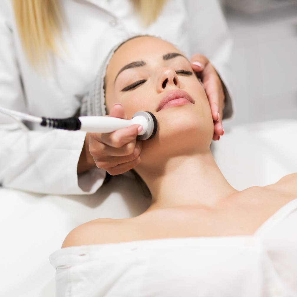 Realizando radiofrequência facial em paciente mulher.