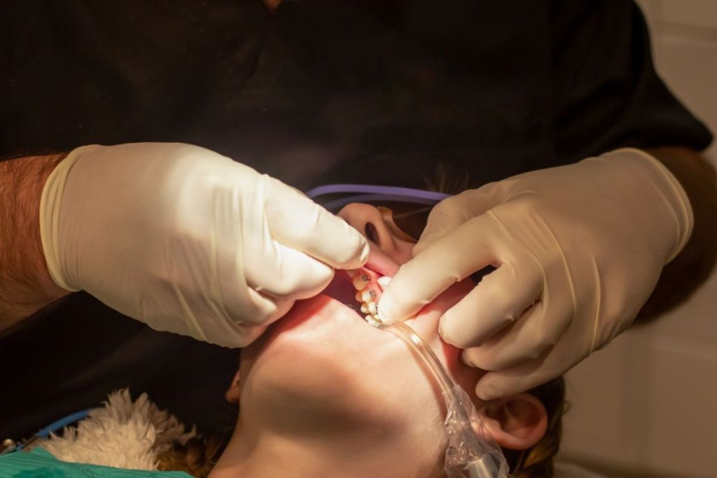 Dentista ajustando aparelho ortodôntico.
