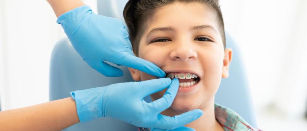 Dentista ajustando aparelho ortodôntico em criança.