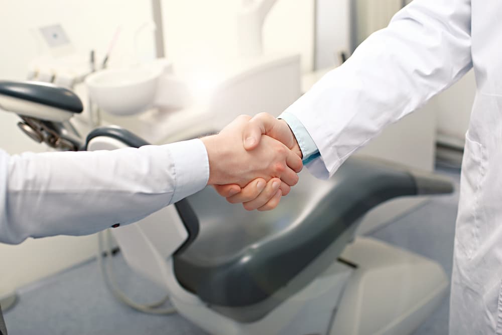 Dentistas dando um aperto de mãos no consultório.