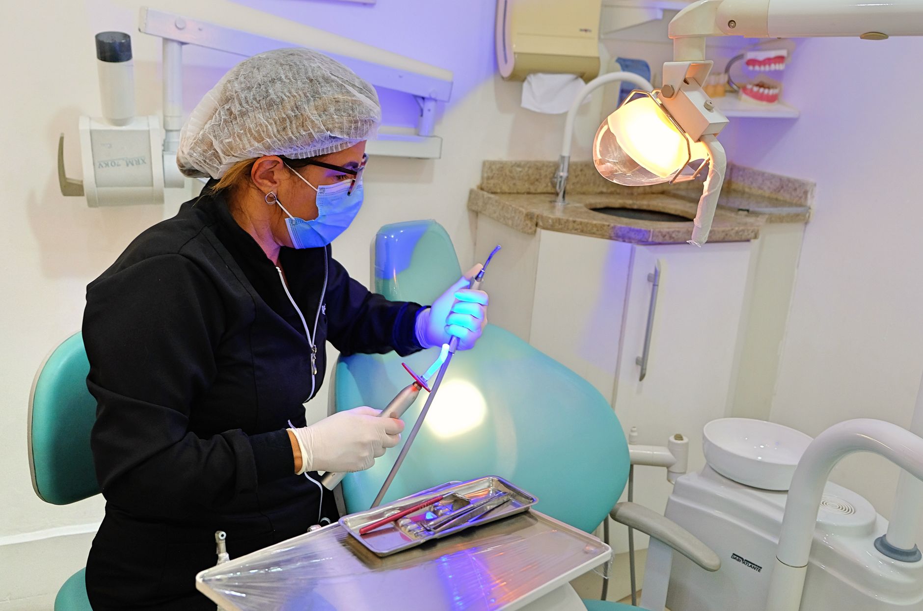 Dentist in clinic using dental tools and equipment for patient care.
