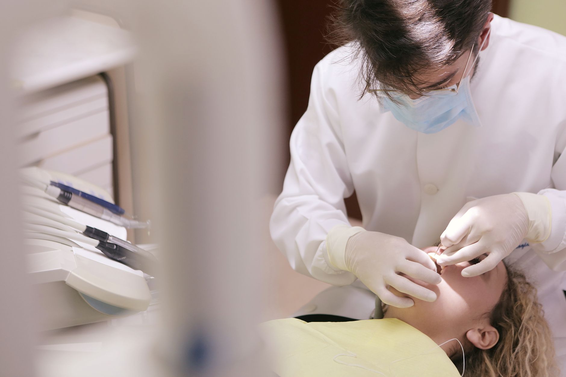 Dentist in mask and gloves providing dental care to a patient in the clinic.