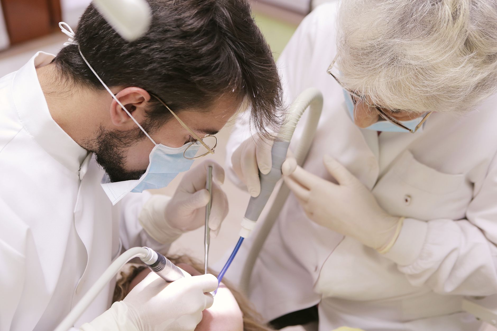 Two dental professionals conducting a treatment in a clinic setting.