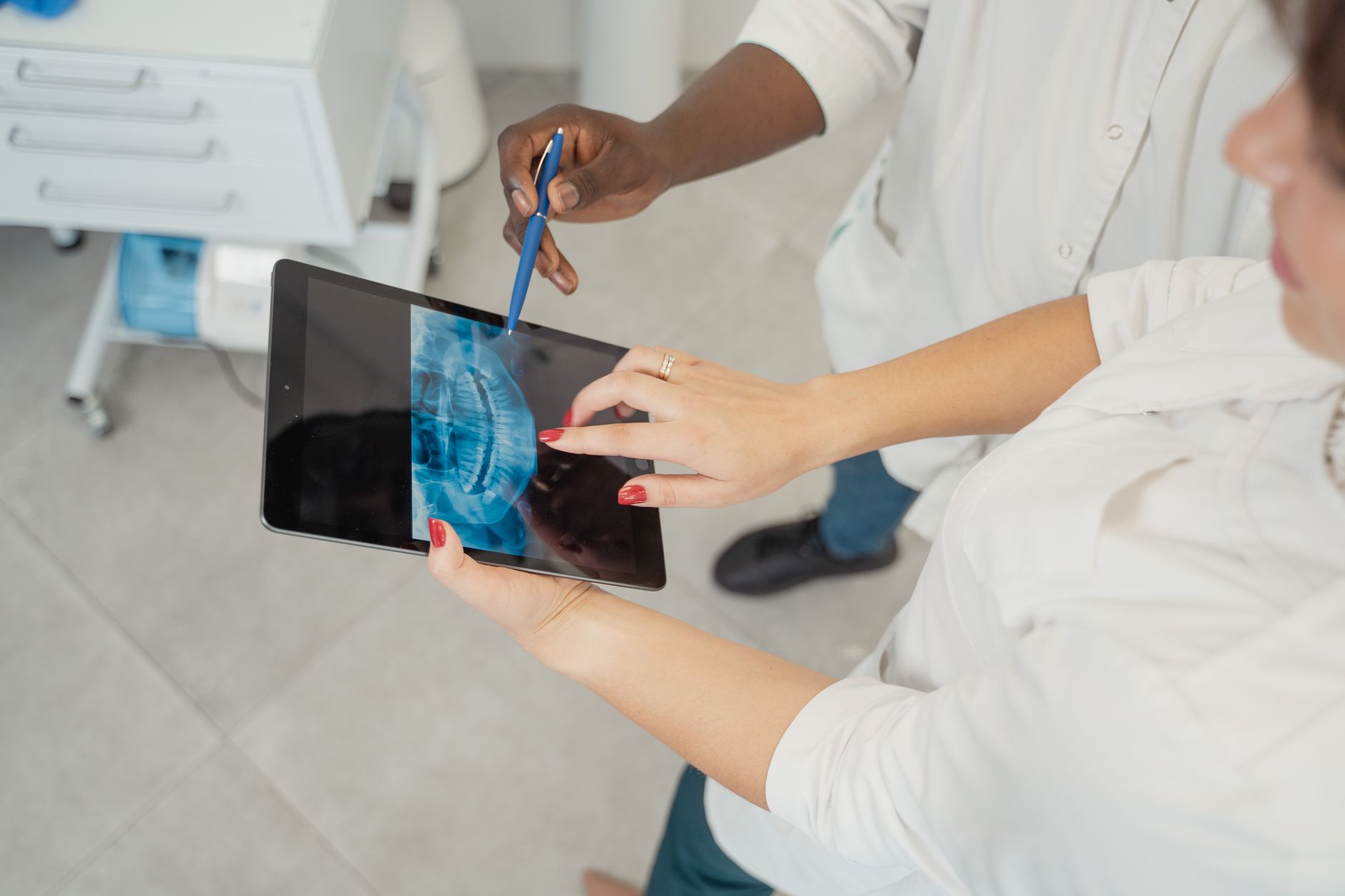 Dentist examining a dental x-ray on a tablet with patient in a modern clinic.